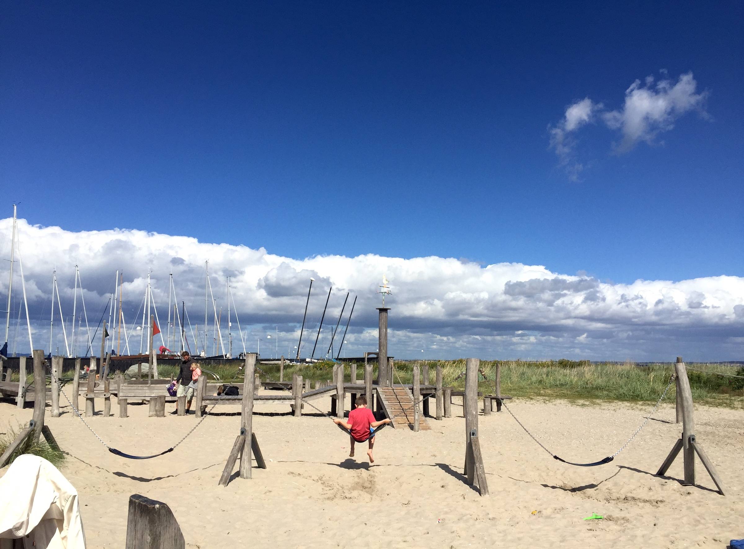 Sandfläche am Hafen mit Spielgeräten aus Holz