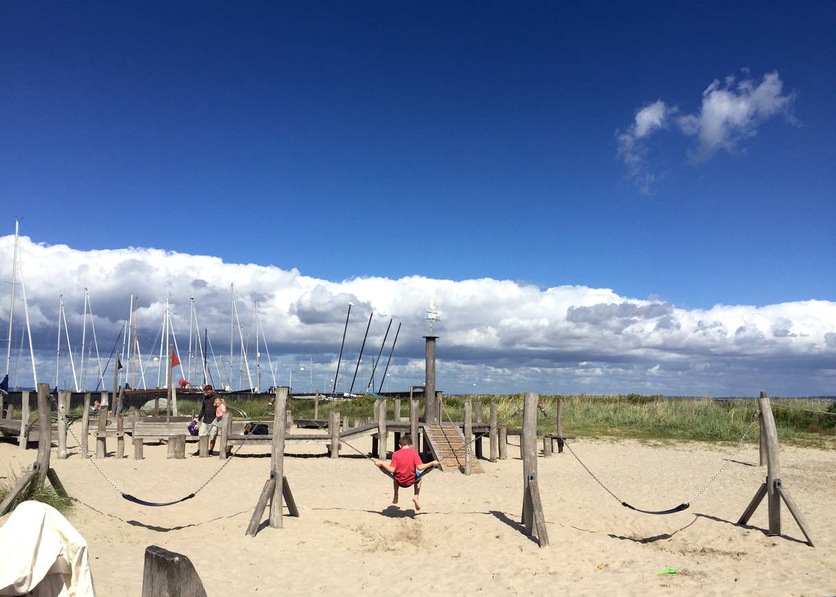 Sandfläche am Hafen mit Spielgeräten aus Holz
