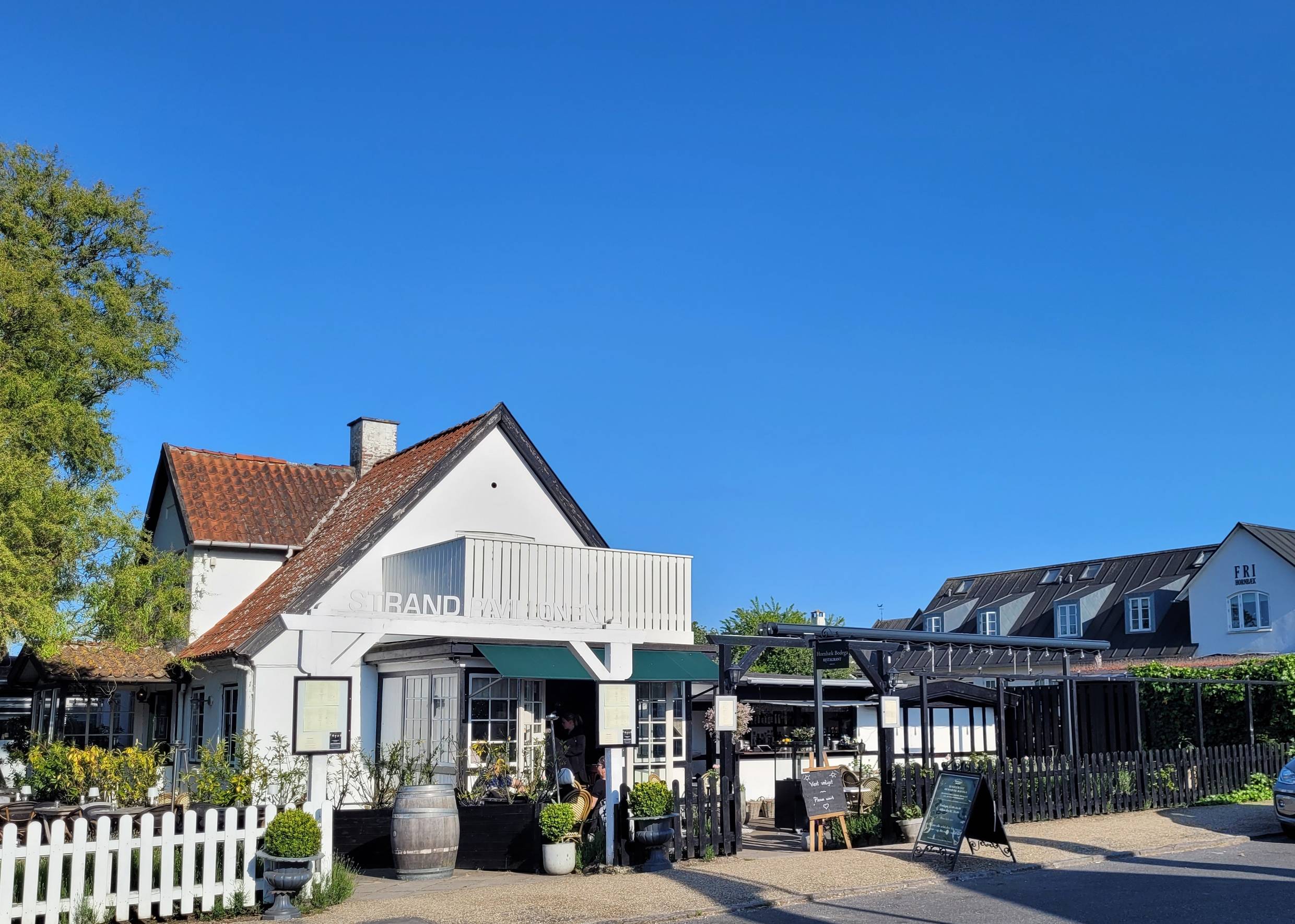 Weißes Haus mit einer schön geschmückten Gastterrasse um das Gebäude