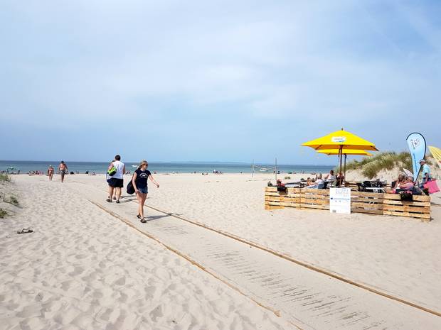 Holzsteg auf dem Strand mit Badegästen