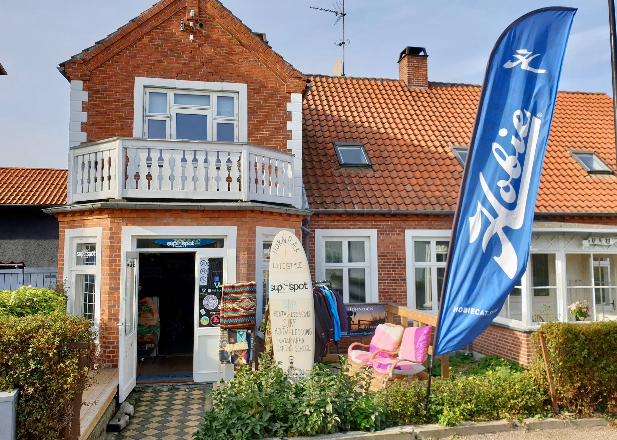 Rotes Wohnhaus mit einem Geschäft für Dekorationen und Sup-Board-Verleih