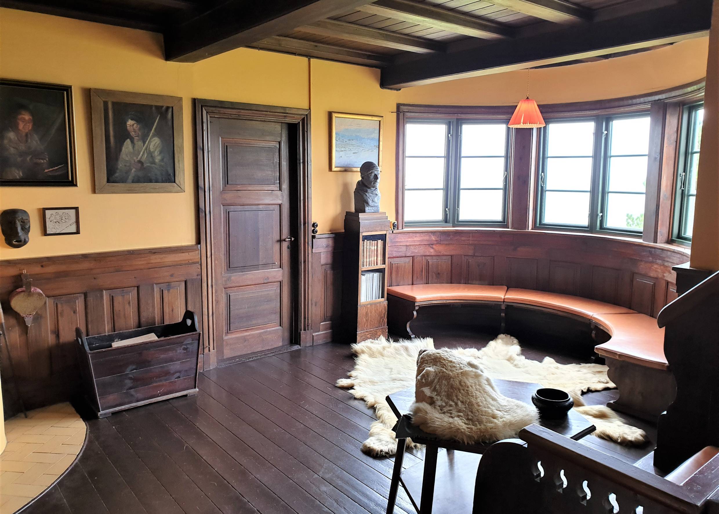 Wohnraum in einem Museum, viel dunkles Holz, Malerei, Schafsfelle