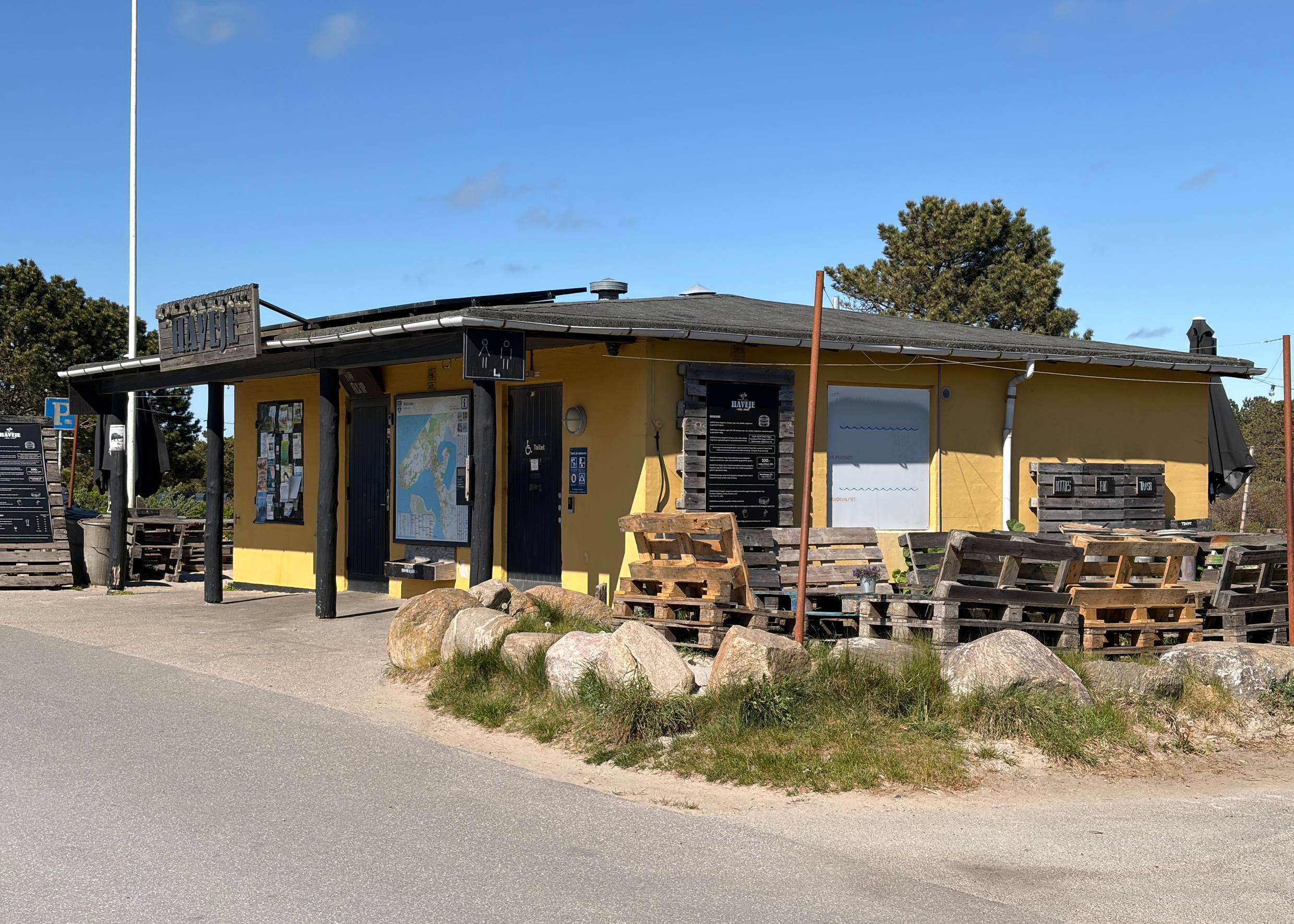 Kleines, gelbes Häuschen mit Toilettenschild und das Menu des Cafés 