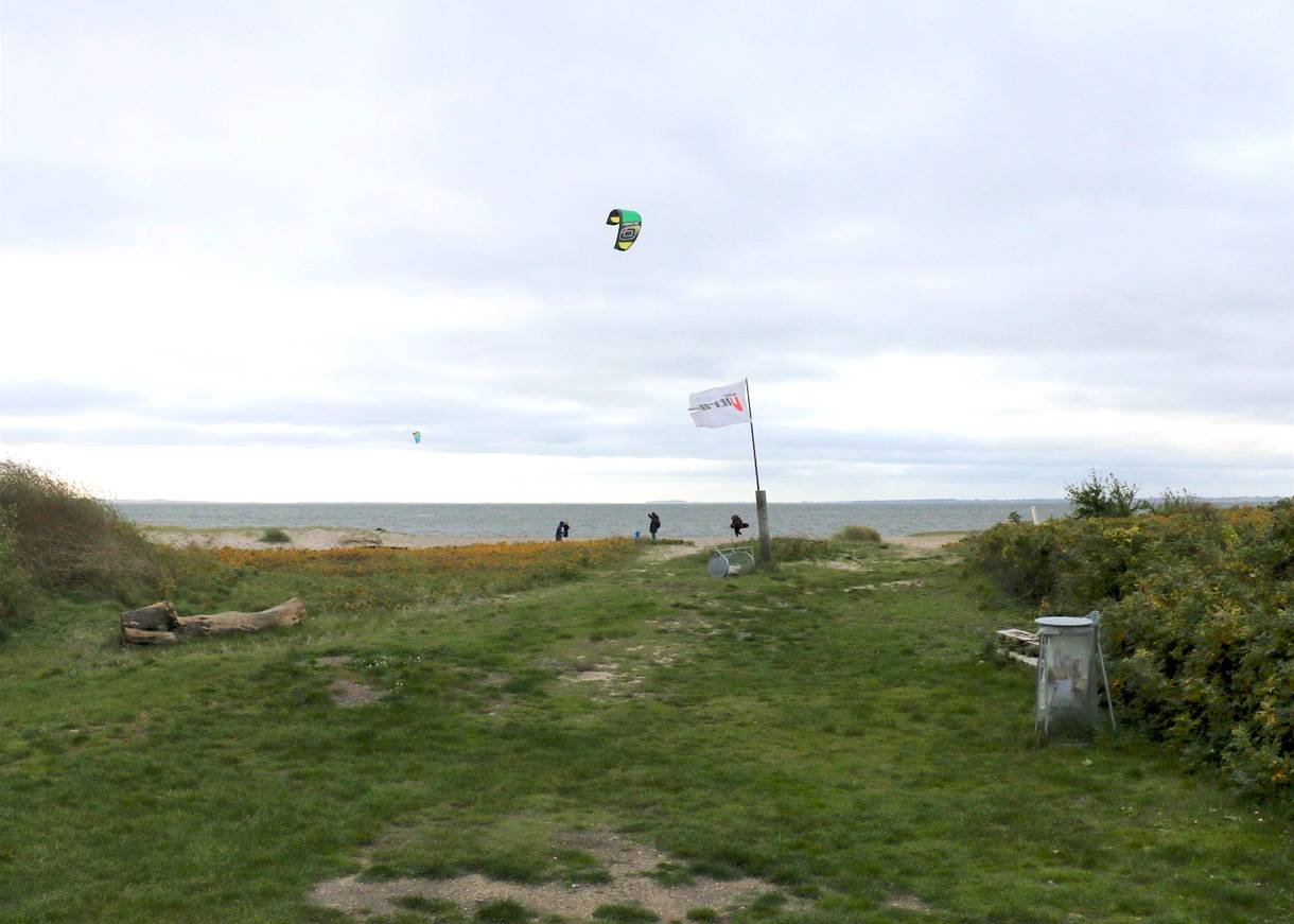 Kitesurfer vor grauem Himmel am Fjordufer