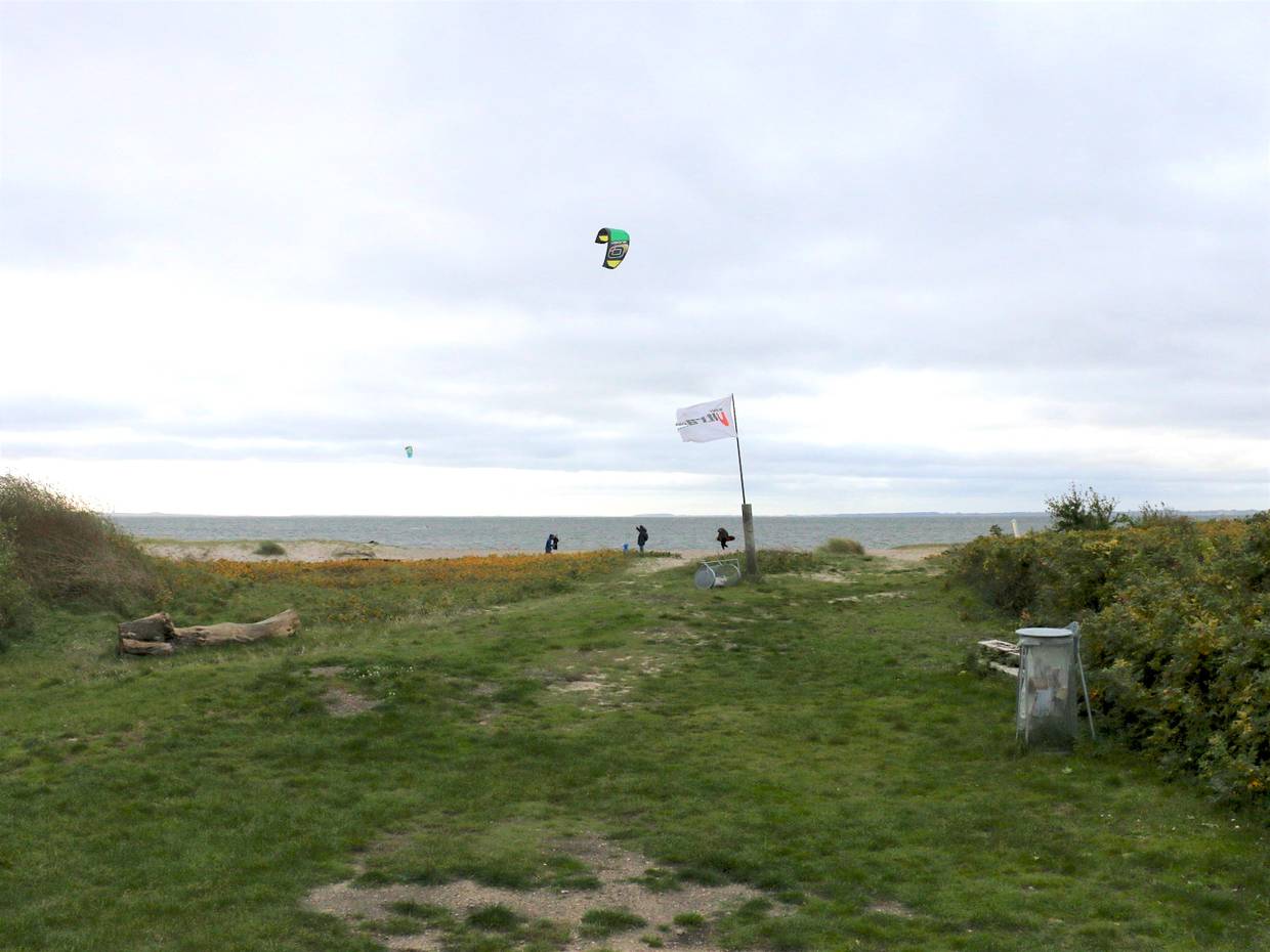 Kitesurfer vor grauem Himmel am Fjordufer