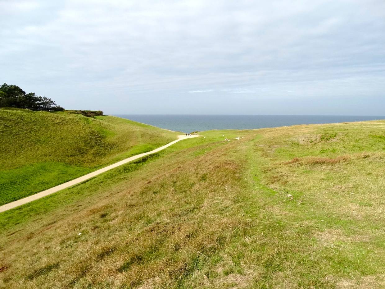 Fußweg zwischen grünen Hügeln zum Meer