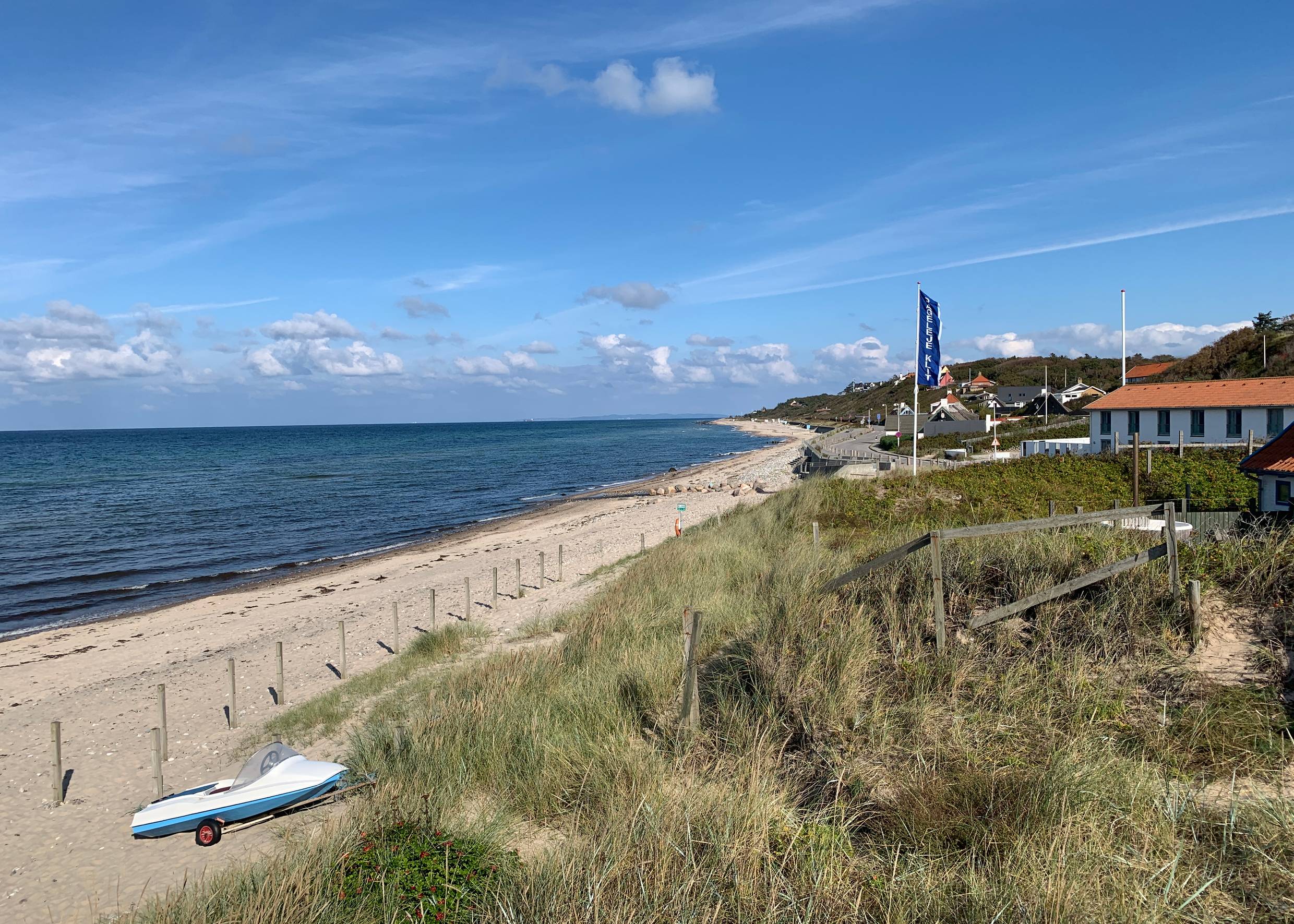 Blick auf einen Strand einigen Häusern und einer Fahne im Hinterrund