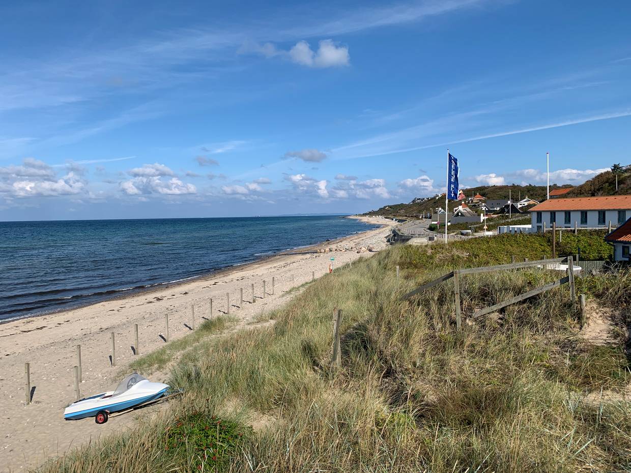 Blick auf einen Strand einigen Häusern und einer Fahne im Hinterrund