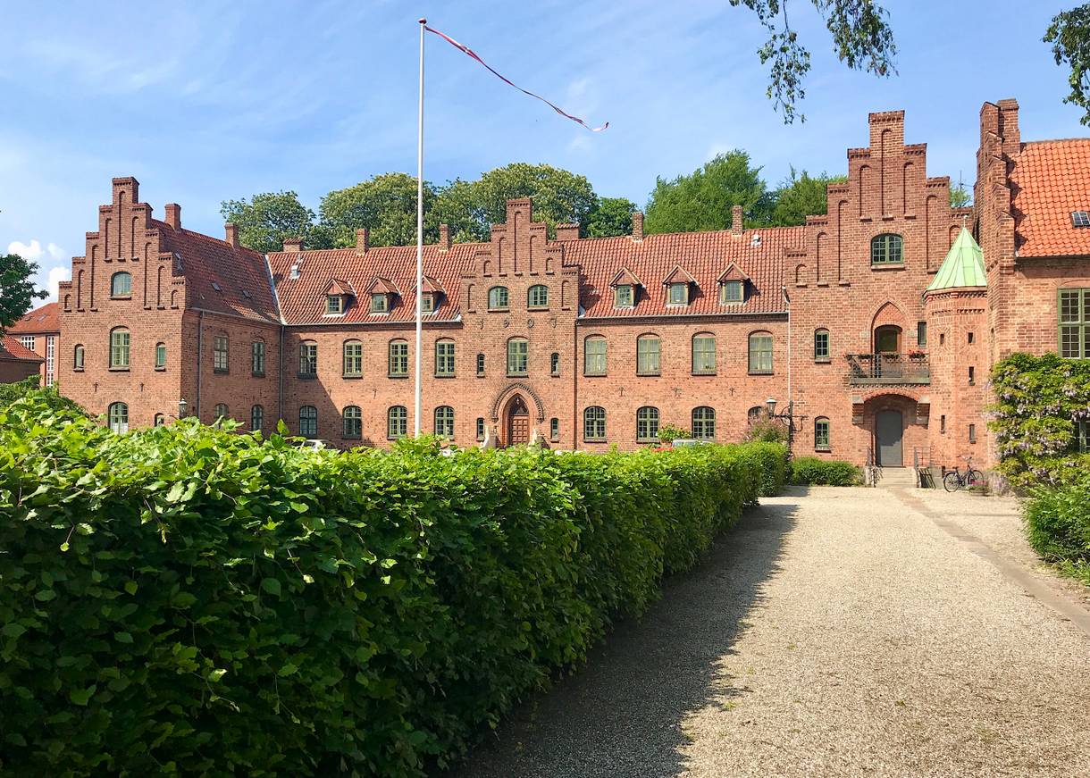 Backsteinkloster mit Treppengiebeln, davor eine Buchenhecke