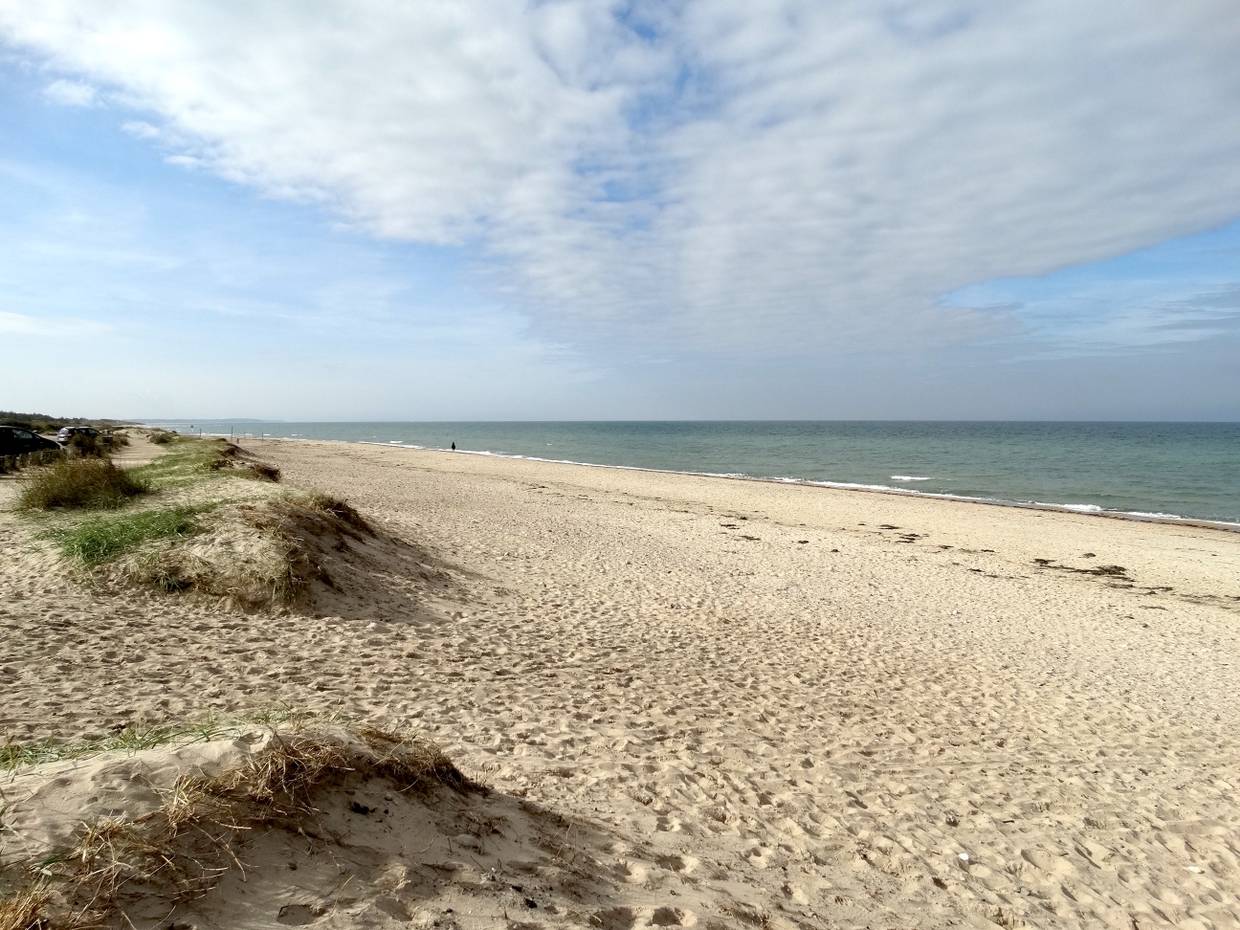 Breiter Sandstrand, in der Ferne ein Spaziergänger