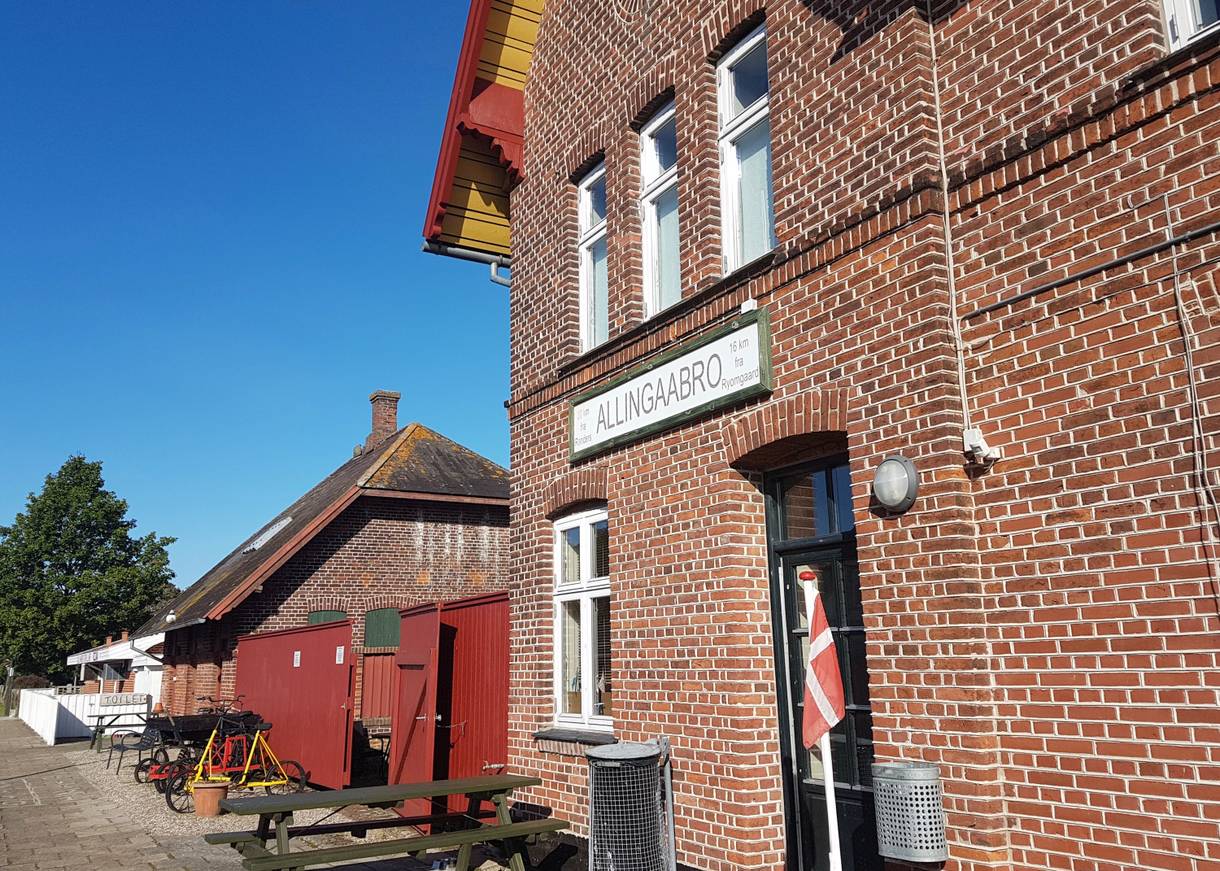 Rotes Backsteingebäude mit Picknickbänken vor der Tür