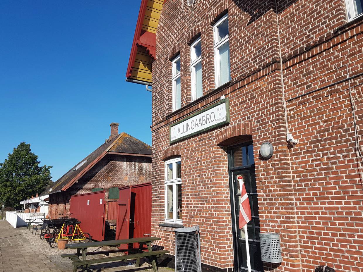 Rotes Backsteingebäude mit Picknickbänken vor der Tür