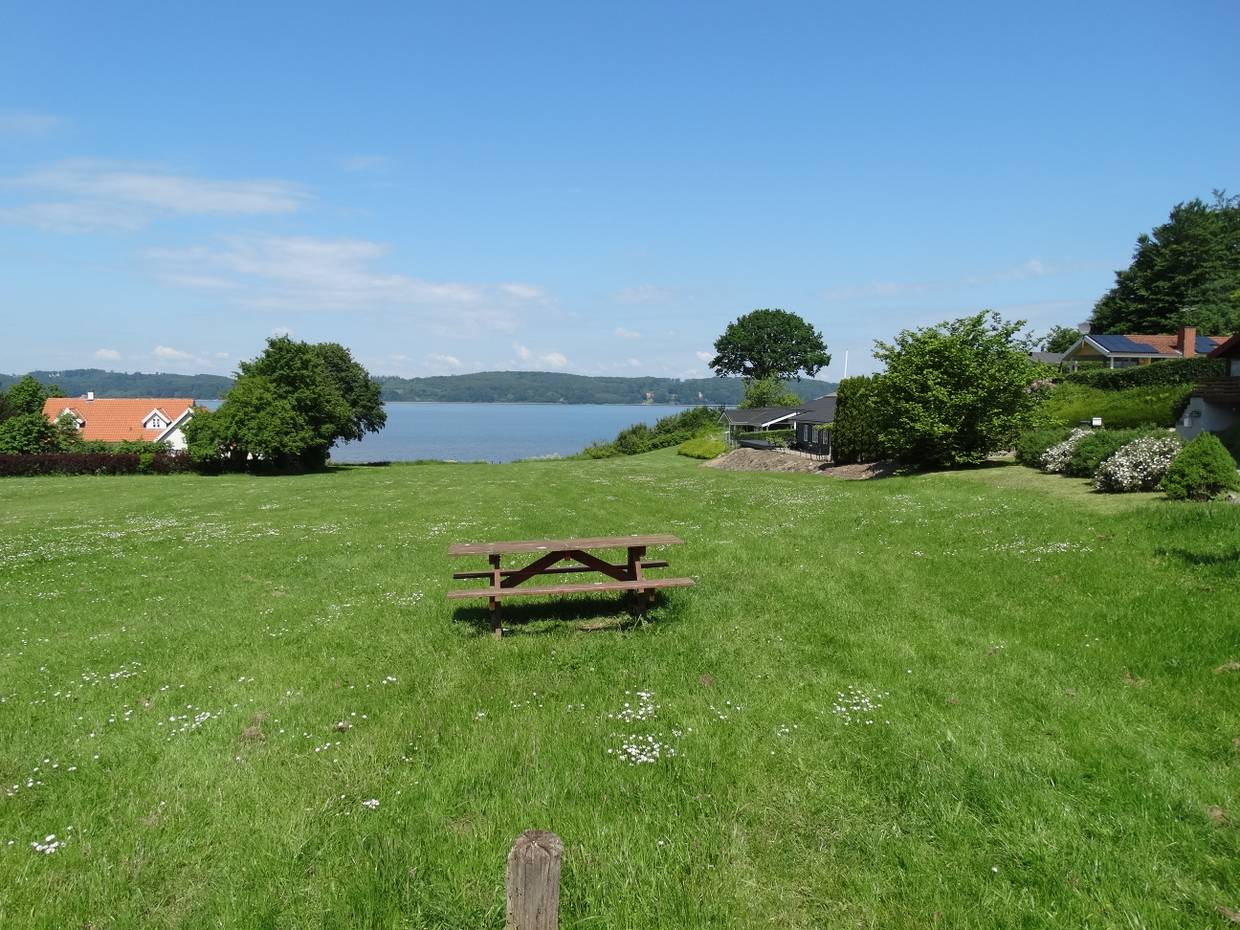 Fjordblick von einem Hügel, auf der Wiese eine Picknickbank