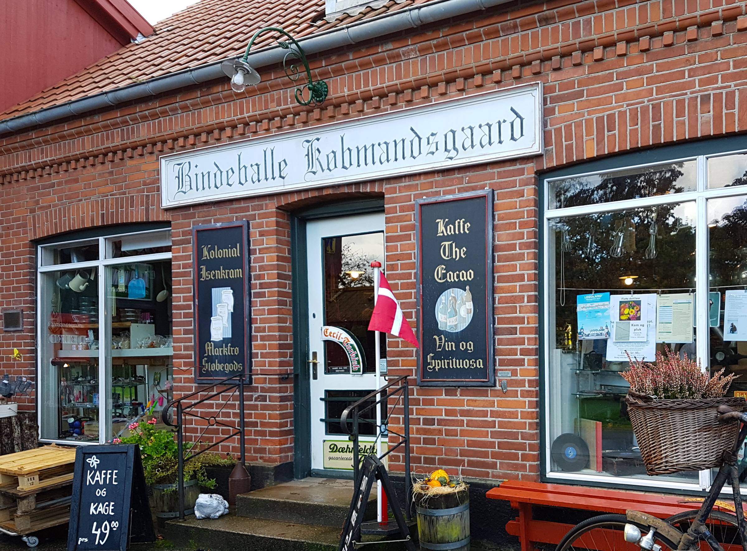 Kaufmann mit alten Schildern über dem Eingang und herbstlicher Dekoration vor der Tür