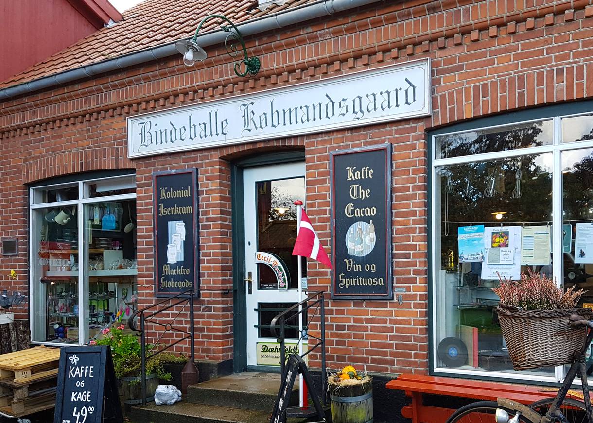 Kaufmann mit alten Schildern über dem Eingang und herbstlicher Dekoration vor der Tür