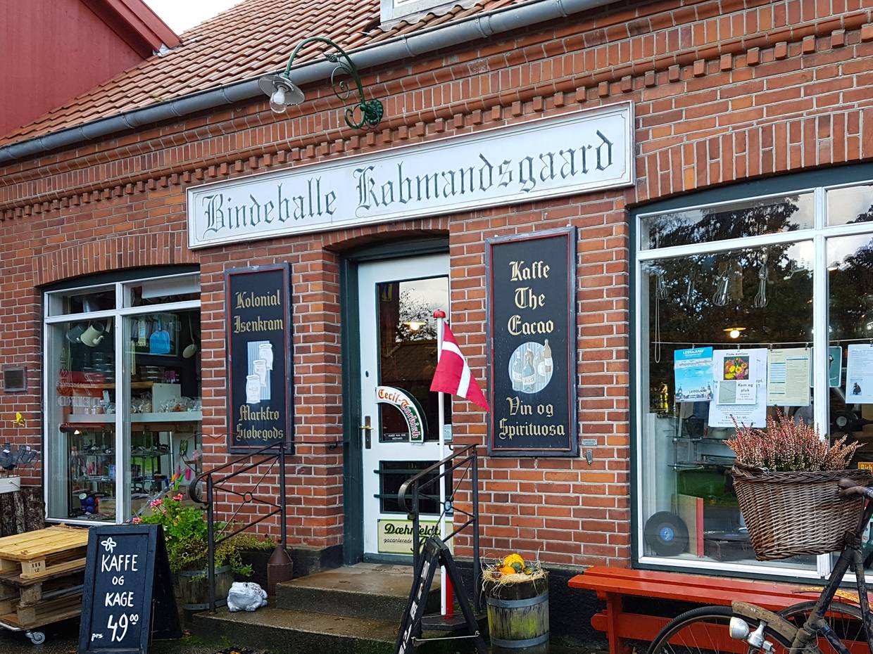 Kaufmann mit alten Schildern über dem Eingang und herbstlicher Dekoration vor der Tür