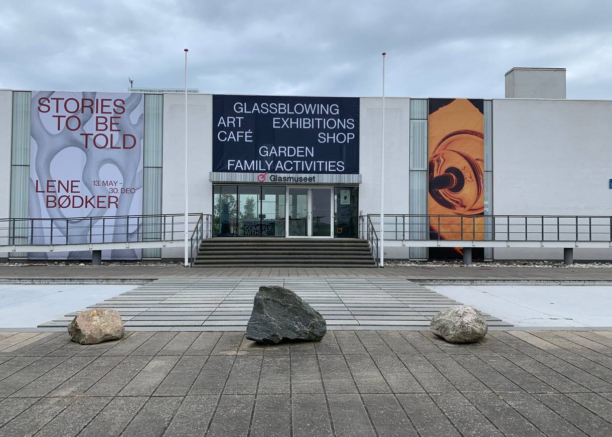 Front des Glasmuseums, ein flaches weißes Gebäude mit großen Farbmosaiken neben dem Eingang
