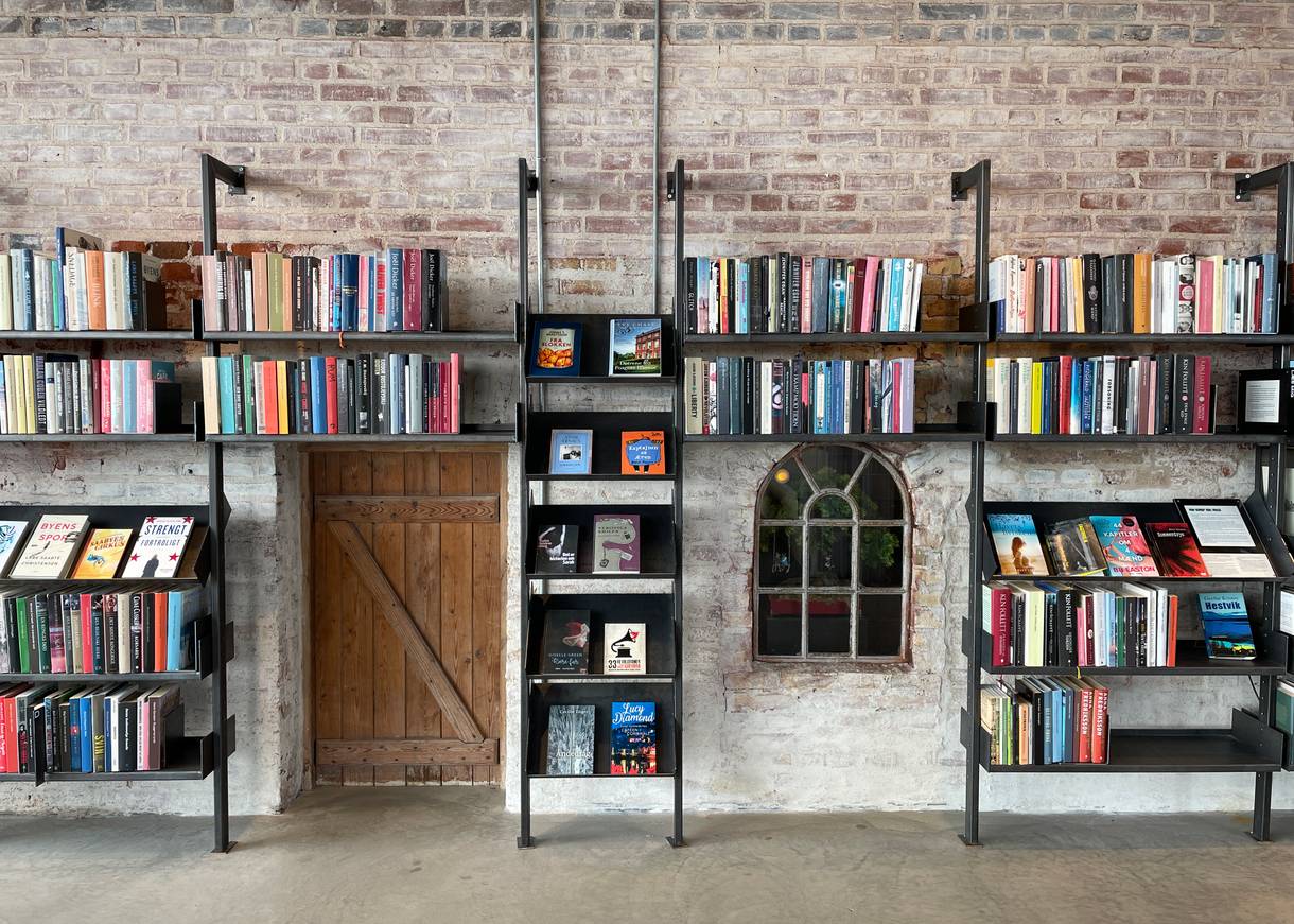 Bücherregal um altes Fenster und restaurierte, alte Gemäuer