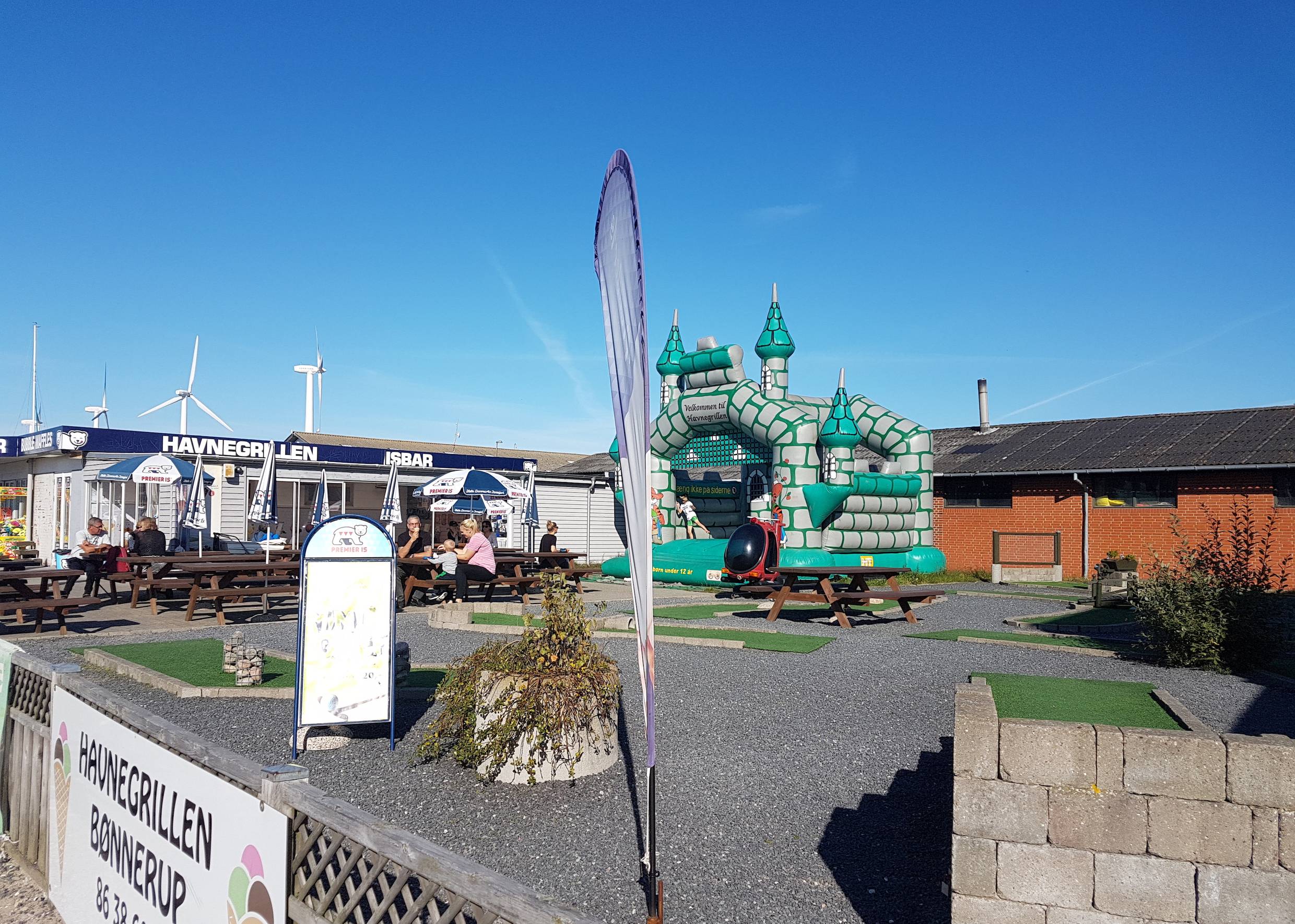 Spielgeräte und Minigolfbahn vor einem Hafenimbiss