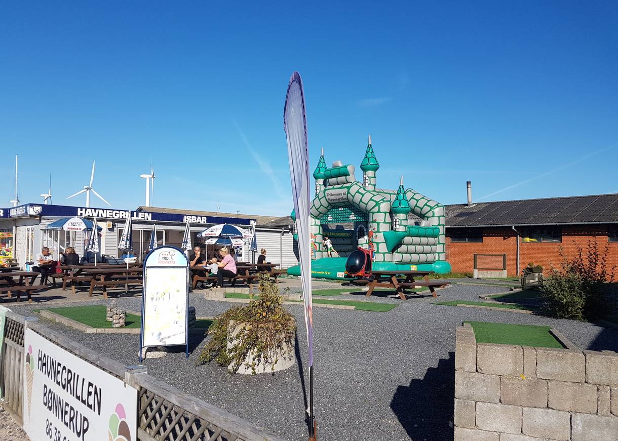 Spielgeräte und Minigolfbahn vor einem Hafenimbiss