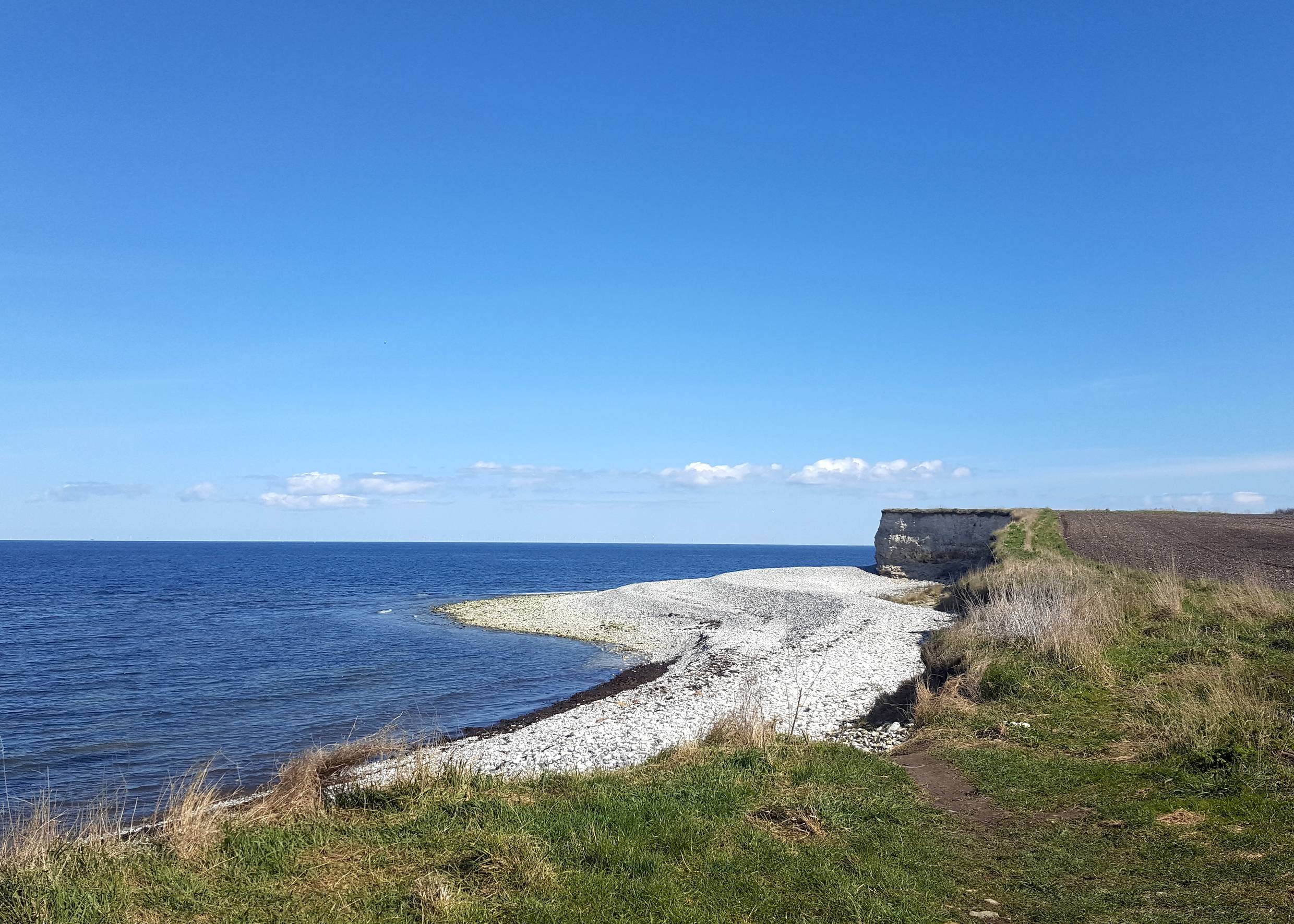 Steinstrand, an dem eine steile Kalsteinküste beginnt
