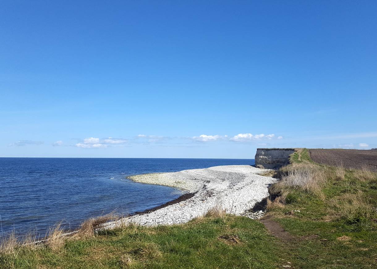Steinstrand, an dem eine steile Kalsteinküste beginnt