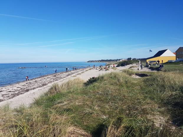 Blick auf einen Sandstrand mit einigen kleinen Häusern am Horizont