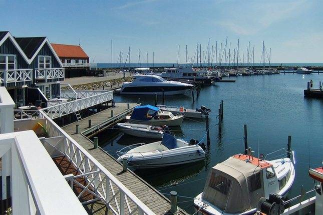 Bootsanleger vor schwarzen Ferienhäusern in der Marina Grenaa