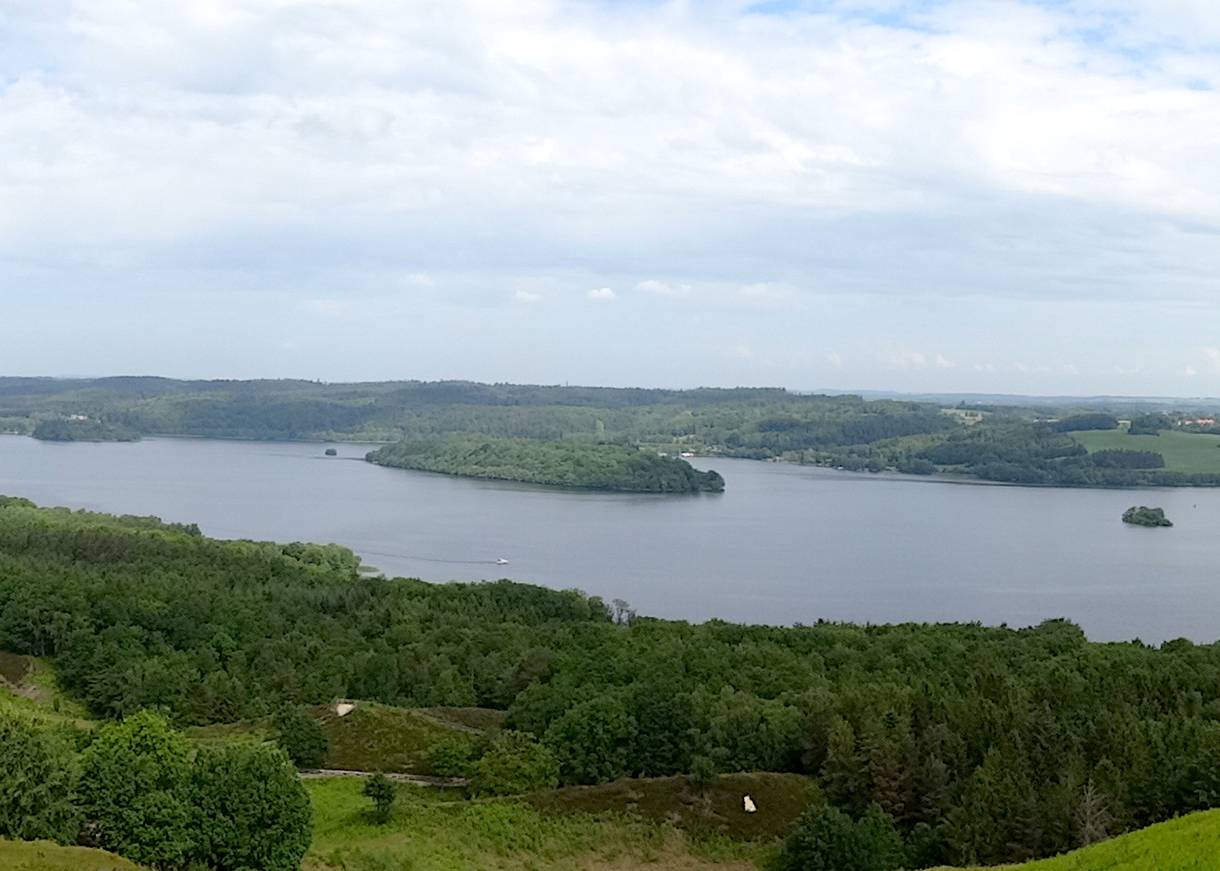 Blauer See in einem Tal, ein kleines weißes Boot auf dem Wasser