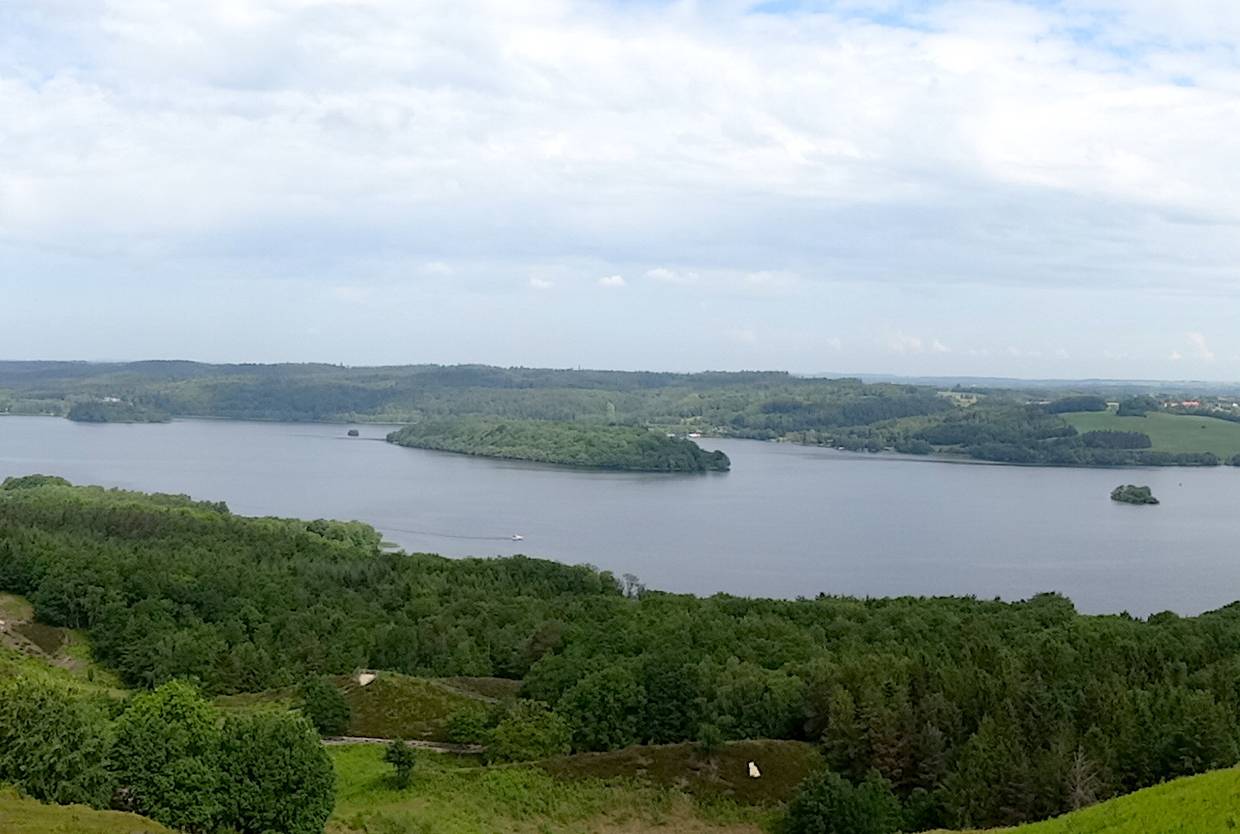 Blauer See in einem Tal, ein kleines weißes Boot auf dem Wasser
