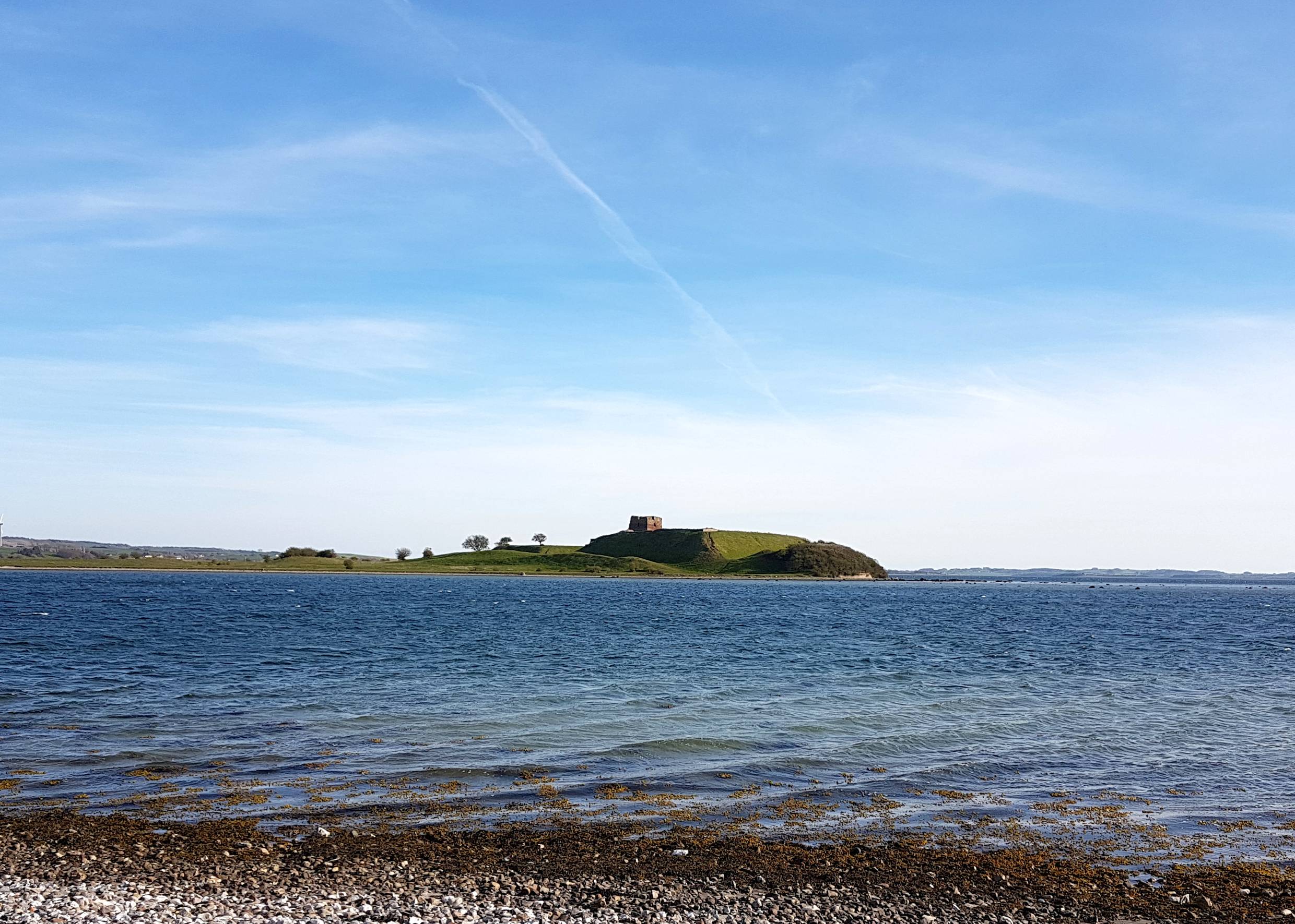 Vorgelagerte Insel mit einer Burgruine auf einem flachen Hügel
