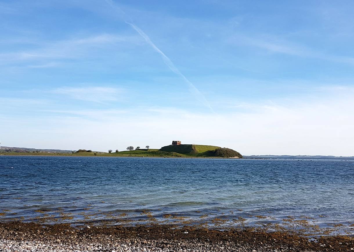 Vorgelagerte Insel mit einer Burgruine auf einem flachen Hügel