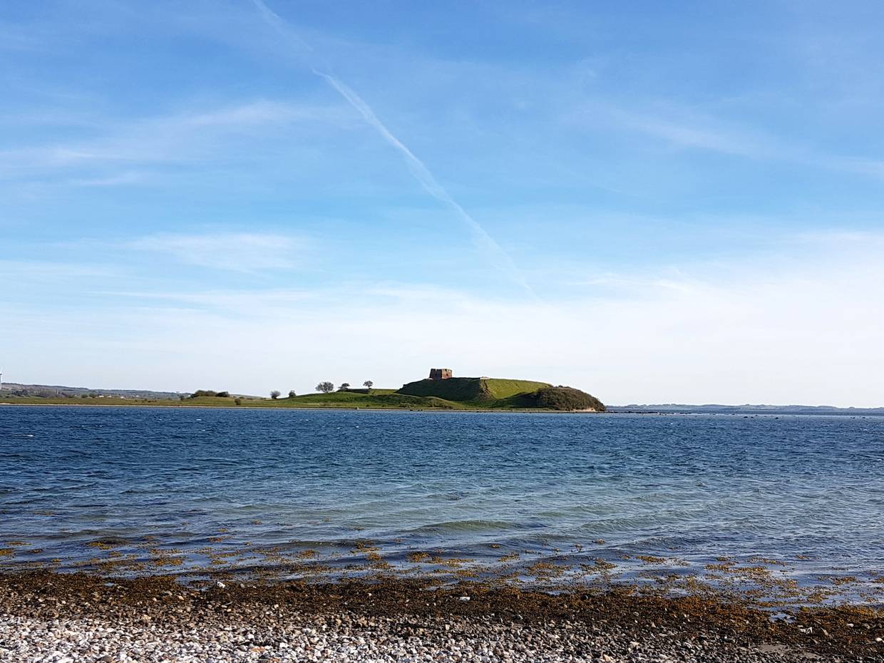 Vorgelagerte Insel mit einer Burgruine auf einem flachen Hügel