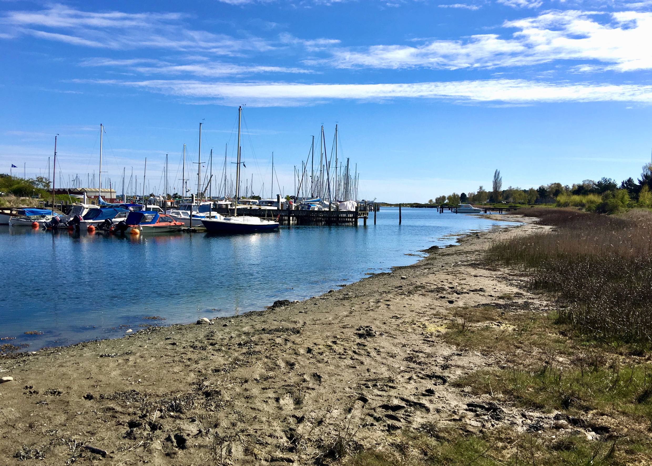 Jachthafen mit Segelschiffen, im Vordergrund etwas matschiger Sand