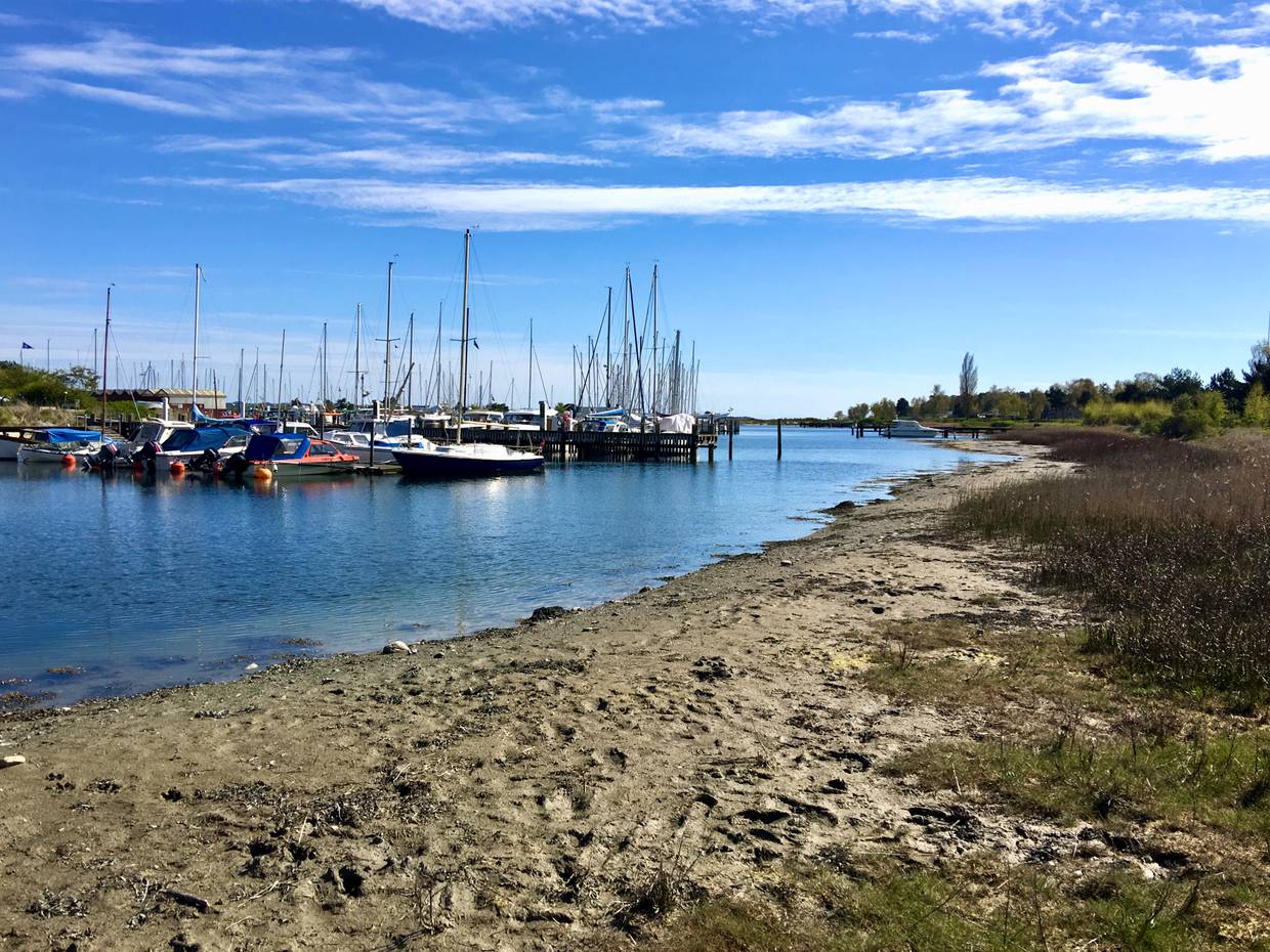 Jachthafen mit Segelschiffen, im Vordergrund etwas matschiger Sand
