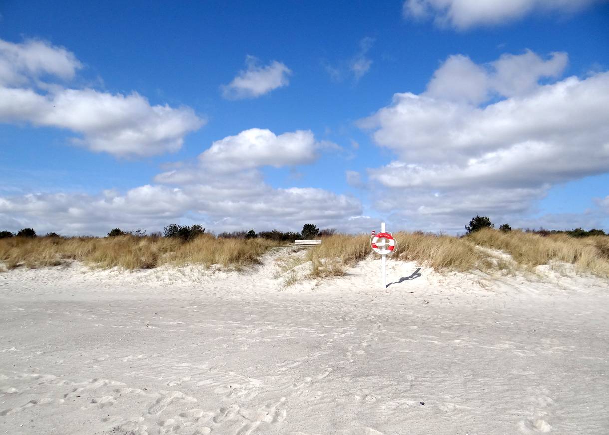 Weißer Sandstrand, in den Dünen eine Bank