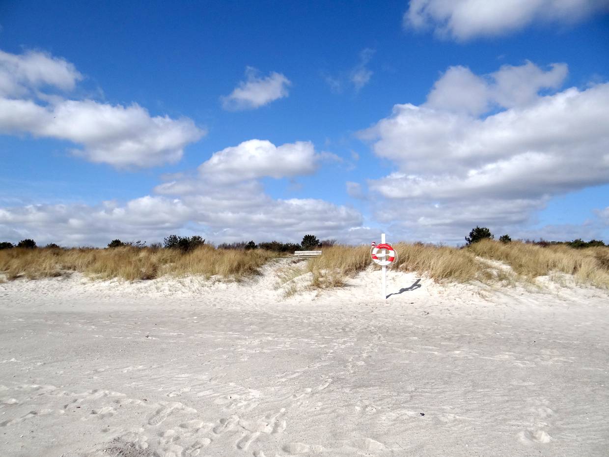 Weißer Sandstrand, in den Dünen eine Bank