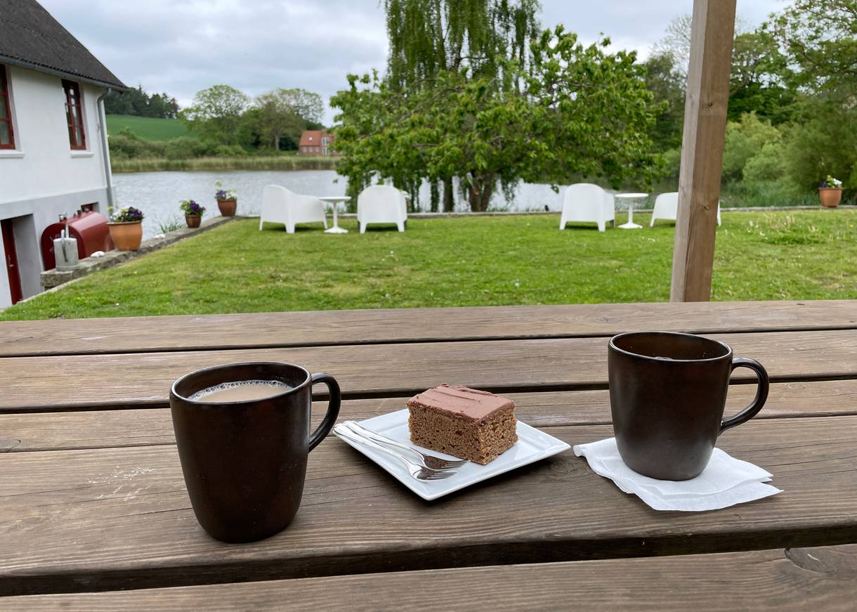 Gefüllte Kaffetassen und hausgemachter Kuchen mit Blick auf einem See