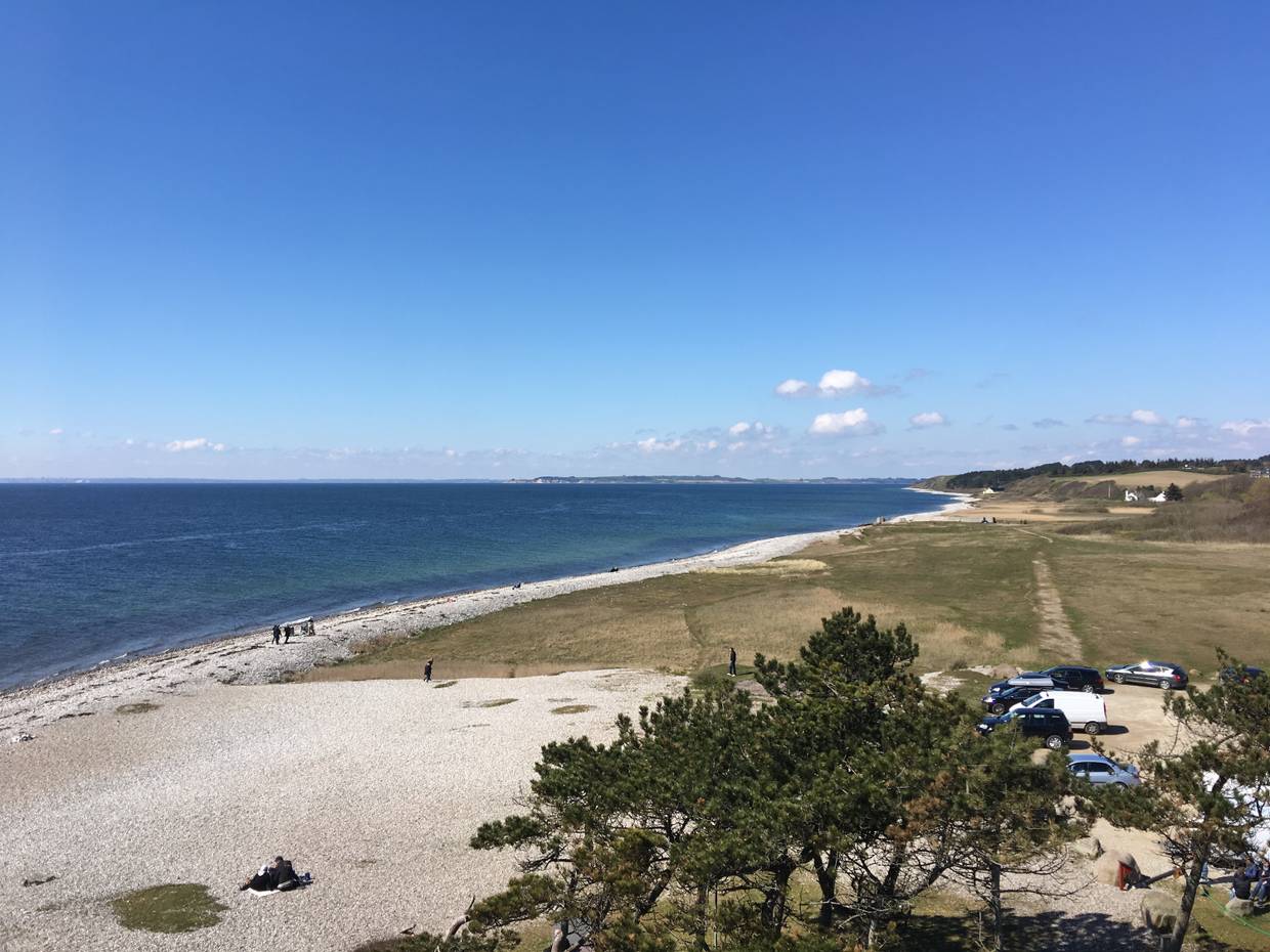 Blick vom Leuchtturm auf Helgenæs auf einen steinigen Strand, im Hintergrund Steilküste