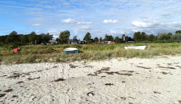 Ferienhäuser direkt am Strand gelegen, davor Ruderboote an Land