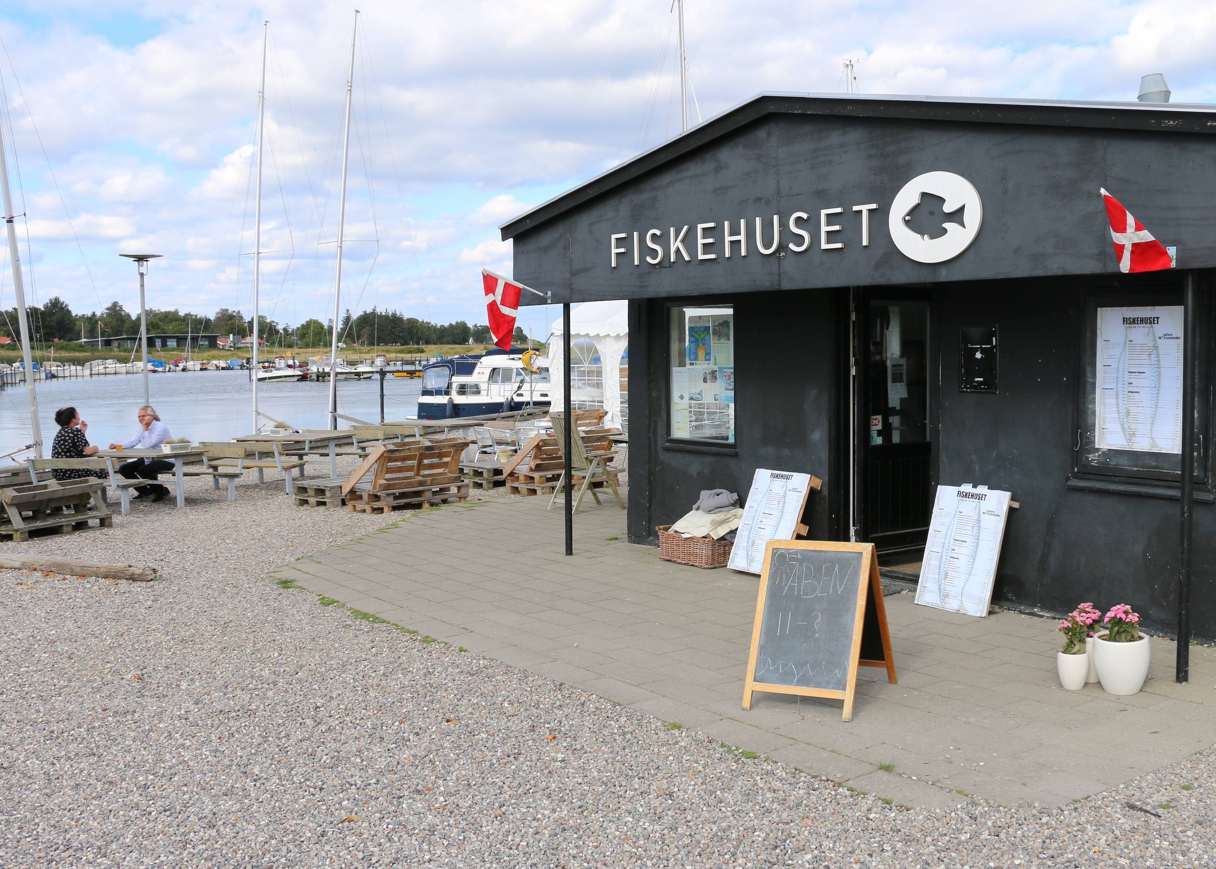 Schwarzes Holzhaus mit Fischlokal am Jachthafen