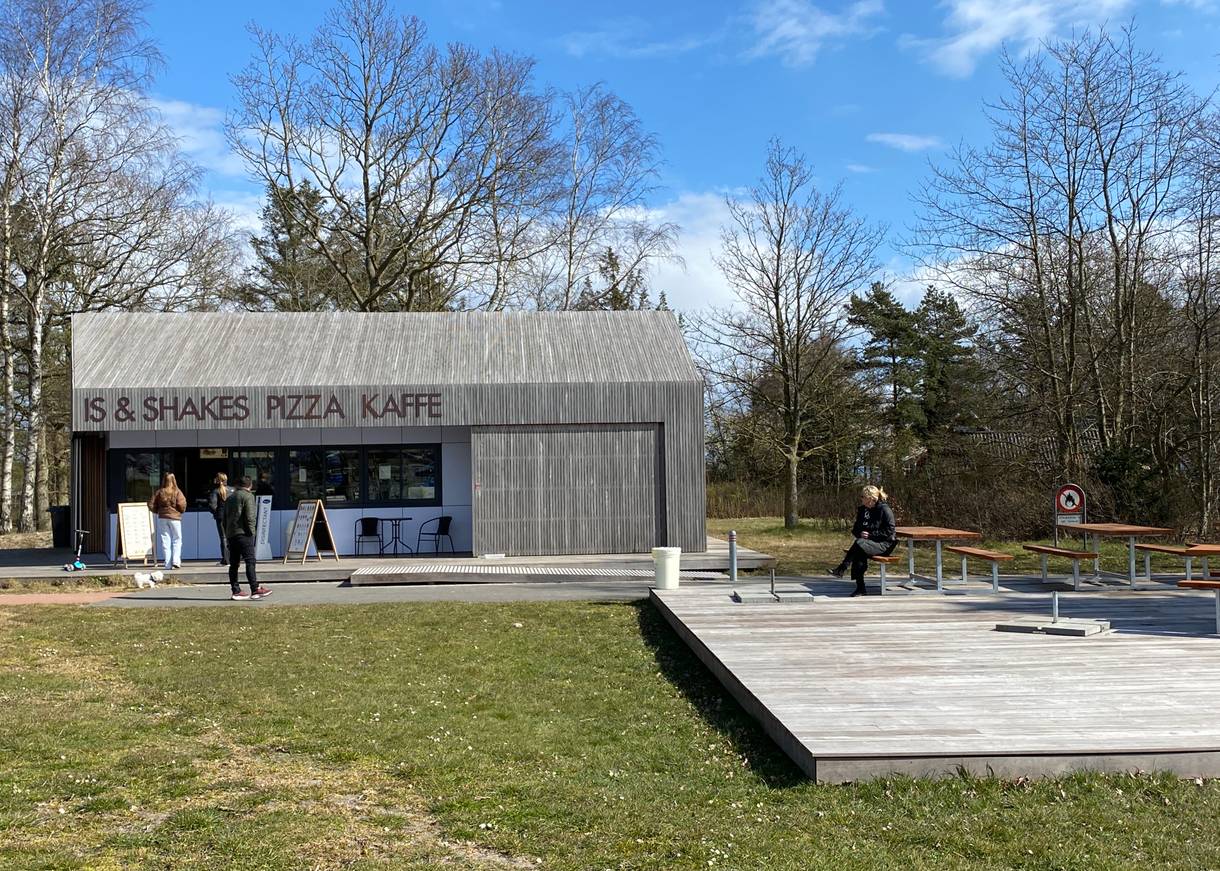 Holzkubus als Strandkiosk, davor eine hölzerne Terrasse