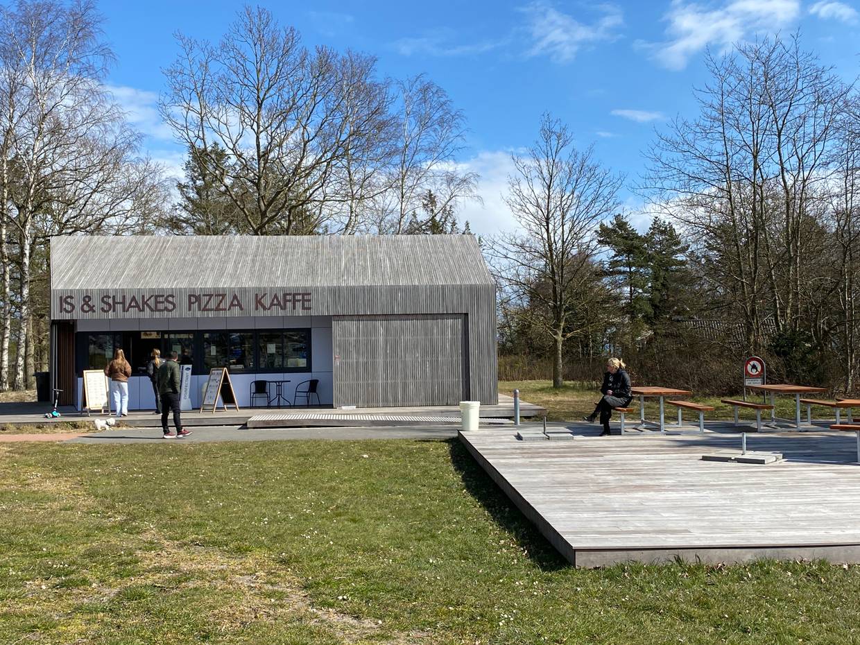 Holzkubus als Strandkiosk, davor eine hölzerne Terrasse