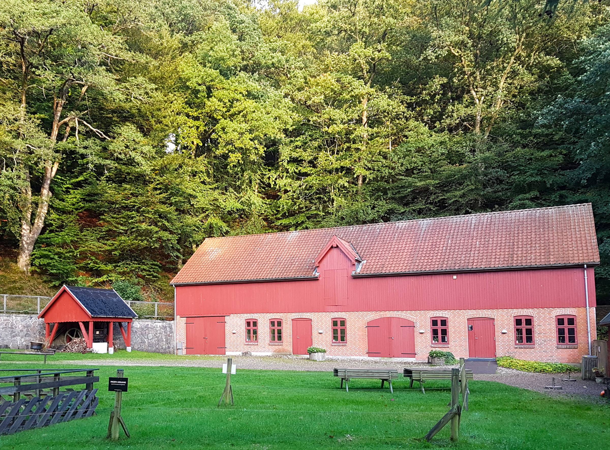 Rotes Haus mit hölzernen Toren, die geschlossen sind, dahinter Wald