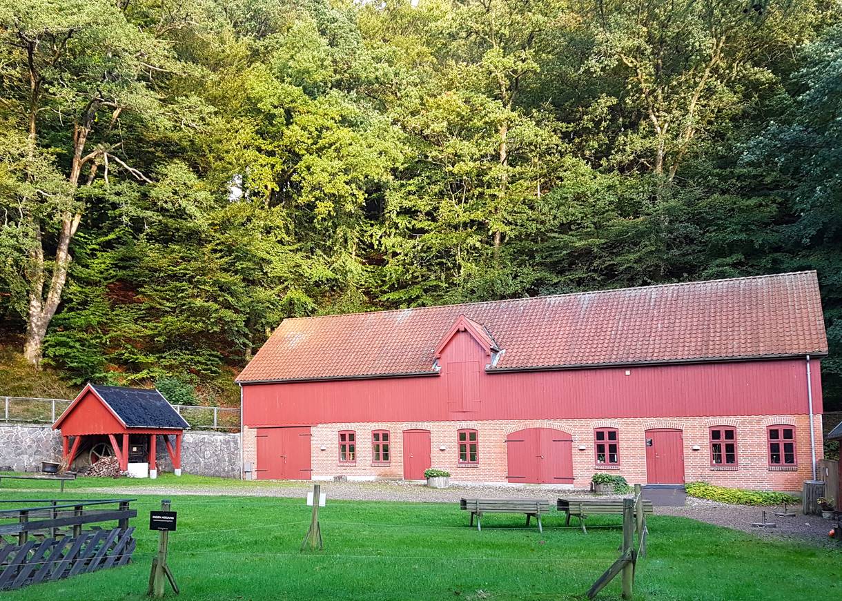 Rotes Haus mit hölzernen Toren, die geschlossen sind, dahinter Wald