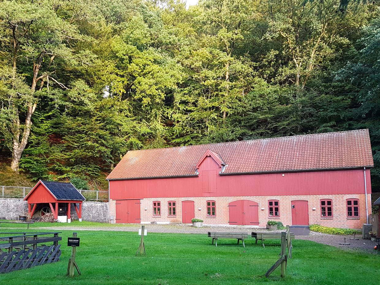 Rotes Haus mit hölzernen Toren, die geschlossen sind, dahinter Wald