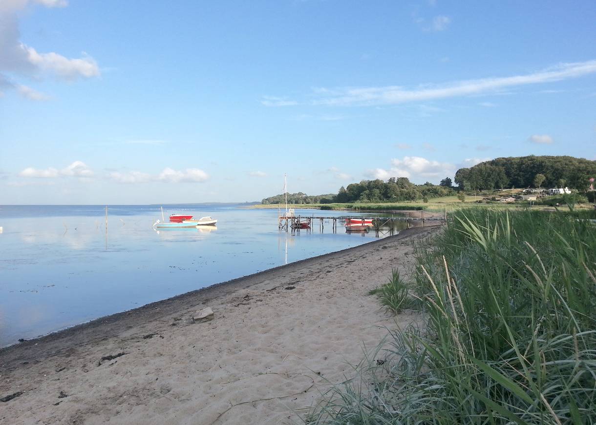 Schmaler, steiniger Sandstrand im Abendlicht