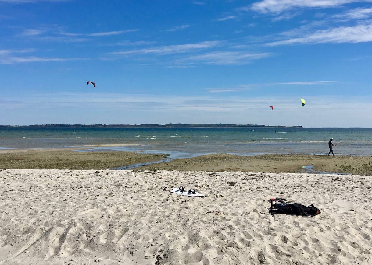 Ein flacher Strand mit Kitesurfern auf dem Wasser
