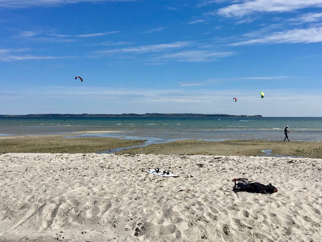Ein flacher Strand mit Kitesurfern auf dem Wasser