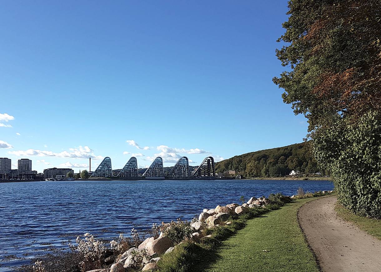 Blick auf vier wellenförmige Häuser am Fjordufer